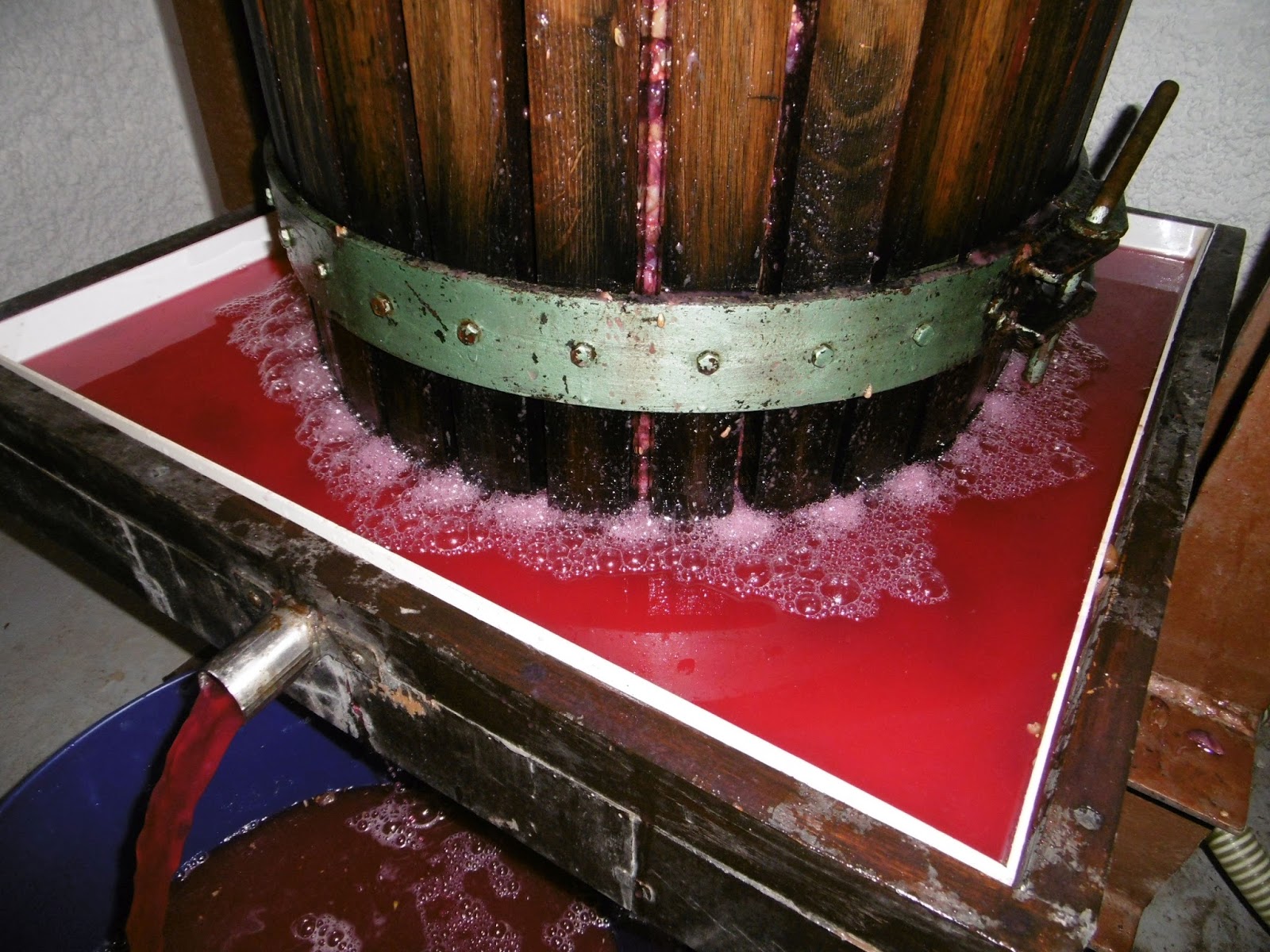 Red fruit juice flowing from a traditional wooden press